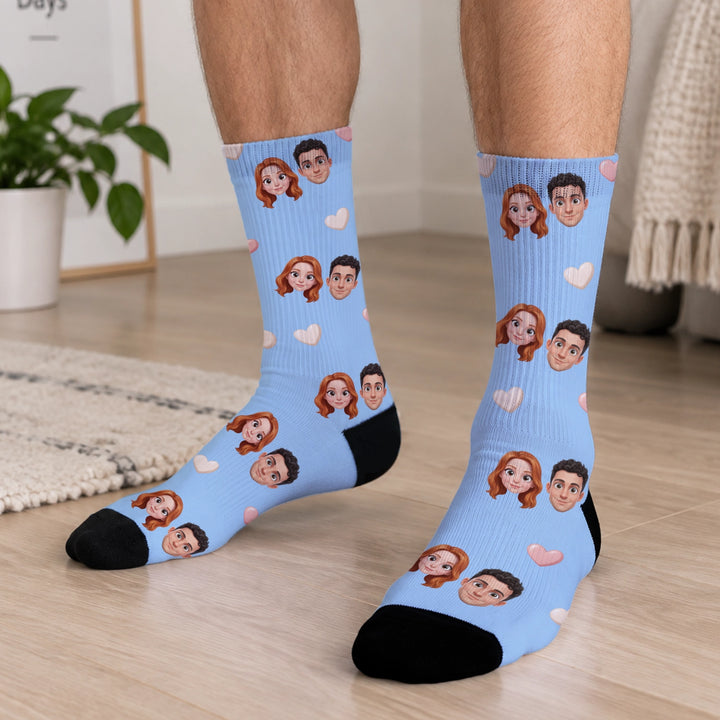 Hellblaue Socken mit zwei Comic-Köpfen eines Paares und Herzen, getragen auf dem Holzboden