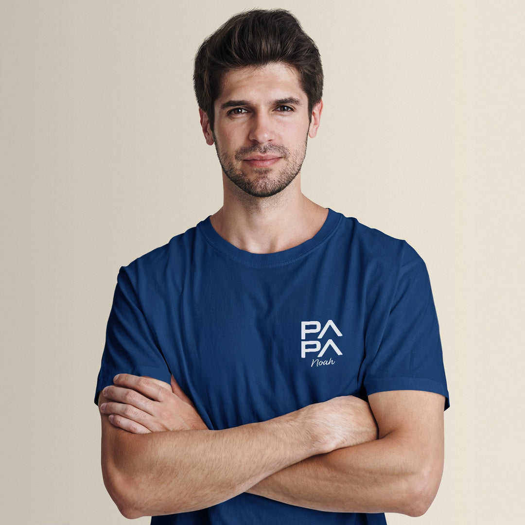 Man wearing a Personalisiertes Papa T-Shirt Modern with arms crossed, featuring personalization option with children's names, ideal for a heartfelt gift.