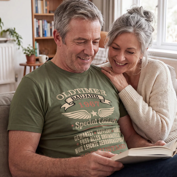 Paar liest auf dem Sofa, er im olivgrünen Oldtimer-Geburtstags-T-Shirt