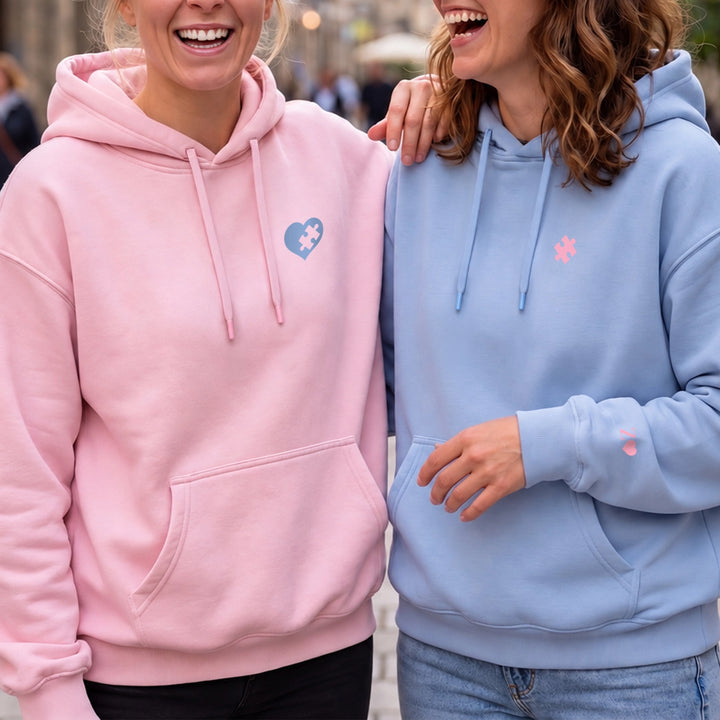 Lachende Freundinnen in rosa und hellblauem Besties-Hoodie mit Puzzle-Motiv