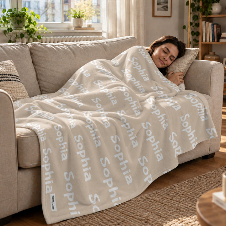 Frau schläft auf dem Sofa unter der beigen Namensdecke
