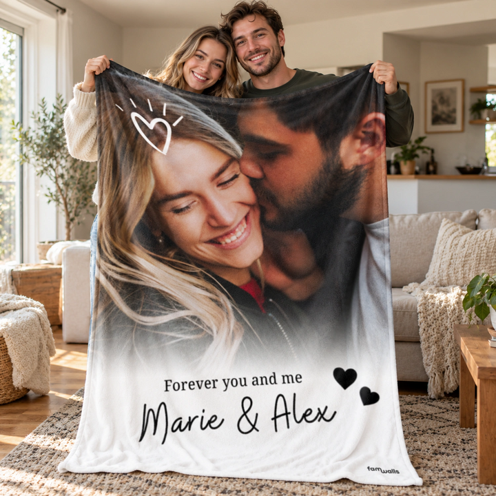 Paar hält die Kuscheldecke mit Paarfoto, Spruch und Namen im Wohnzimmer hoch