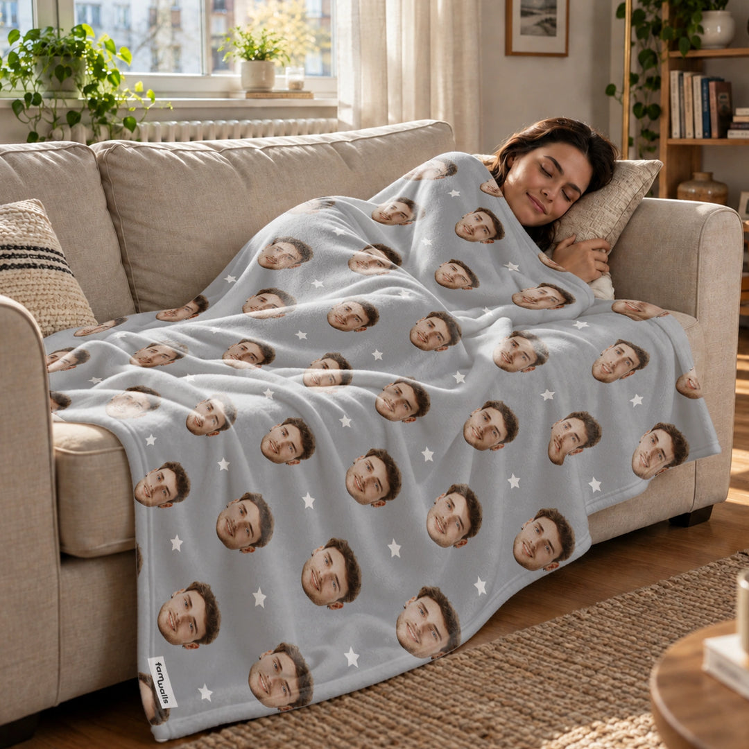 Frau schläft auf dem Sofa unter der grauen Foto-Decke mit Gesichtern und Sternen