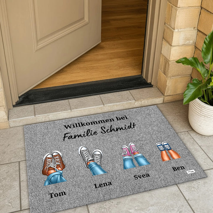Graue Fußmatte Eure Sneaker vor offener Tür mit Willkommensgruß für die Familie